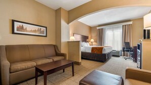 A hotel room with a sofa, a bed, a desk, and a television.