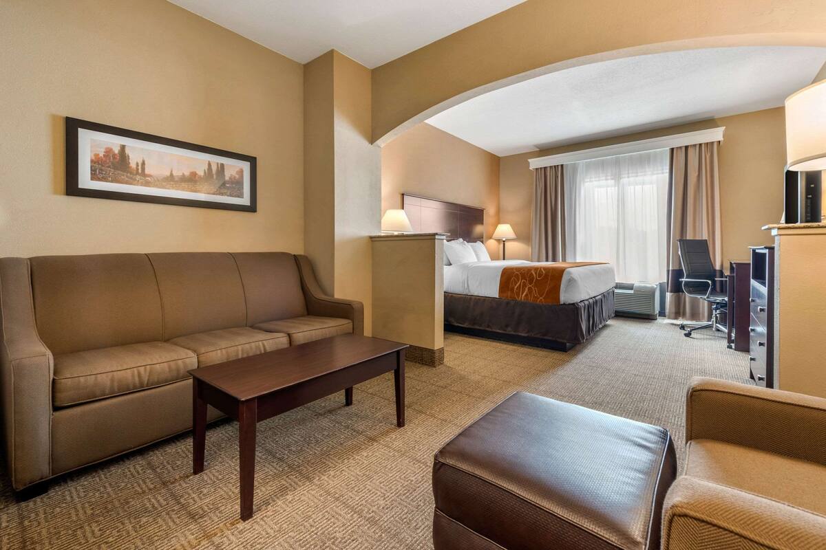 Ein Hotelzimmer mit Sofa, Bett, Schreibtisch und Fernseher.