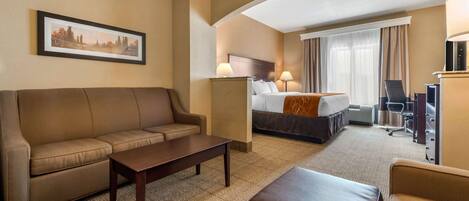 A hotel room with a sofa, a bed, a desk, and a television.