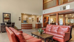 A spacious lobby with leather sofas, a reception desk, and a dining area.