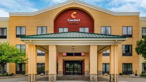 A hotel with a central entrance, a covered waiting area, and a sign reading "Comfort Suites".