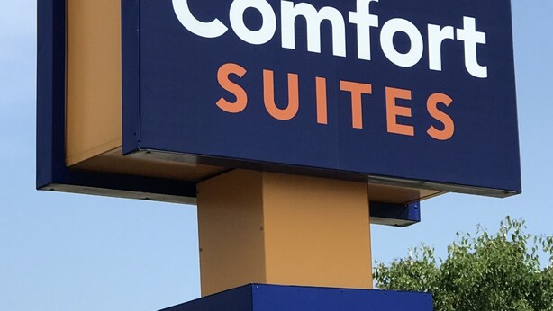 A sign for Comfort Suites with a stylized 'C' logo.