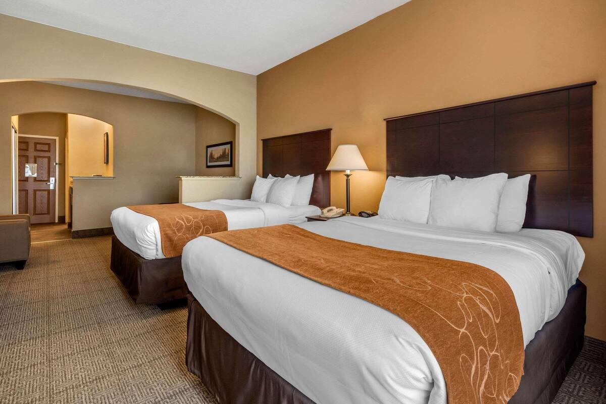 Ein Hotelzimmer mit zwei Betten, einem Schreibtisch, einer Lampe und einem Telefon.