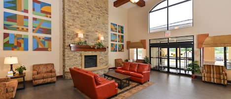 A spacious lobby with a stone fireplace, red leather sofas, and artwork on the walls.