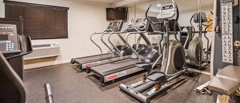 Une salle de sport équipée de tapis de course, d’un vélo elliptique et d’un vélo d’appartement.