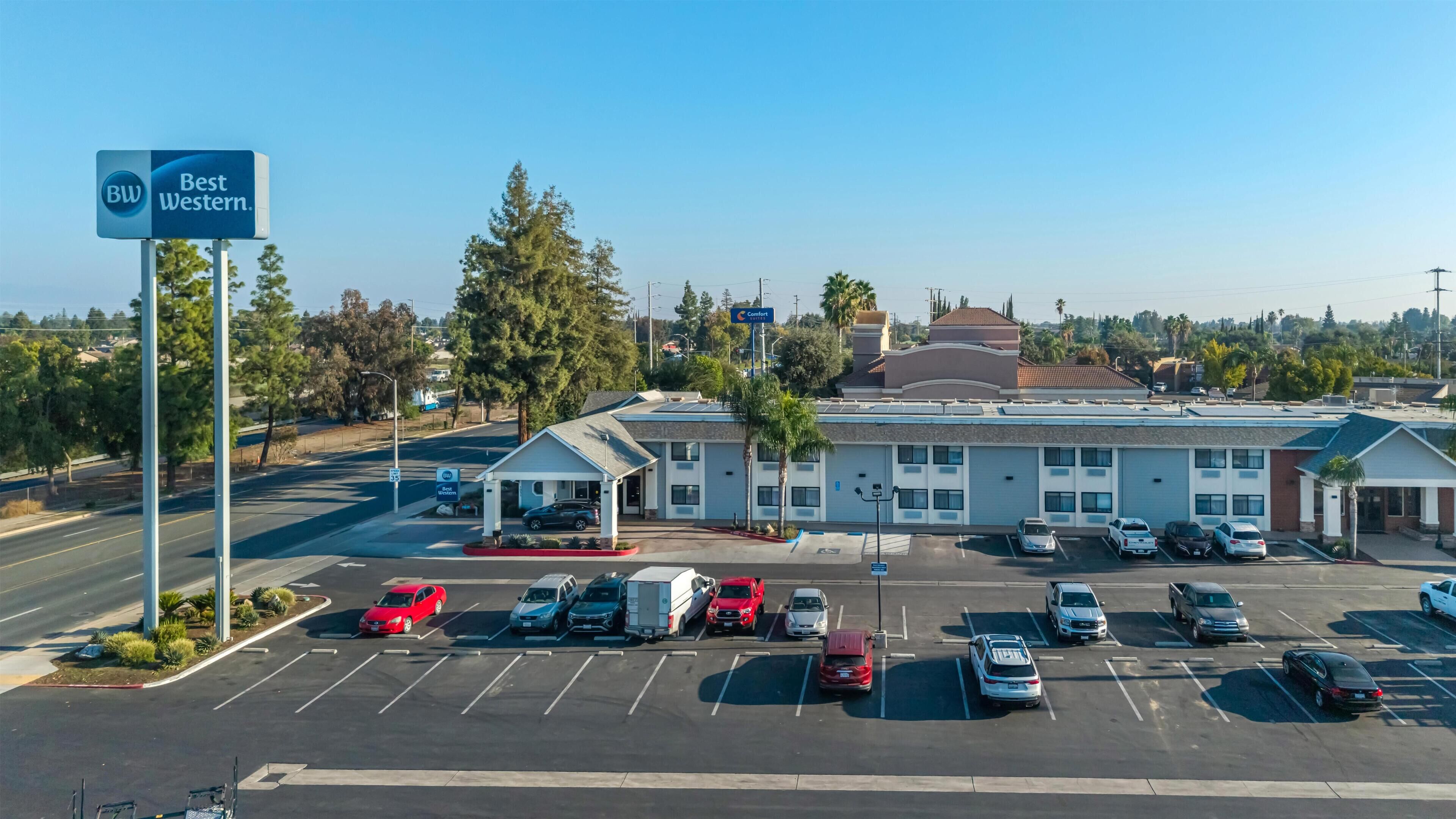 A Best Western hotel with a parking lot, a small attached building, and surrounding trees.