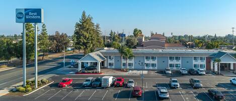 A Best Western hotel with a parking lot, a small attached building, and surrounding trees.
