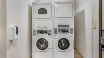 A laundry room with two stacked washing machines and a wall-mounted dryer.