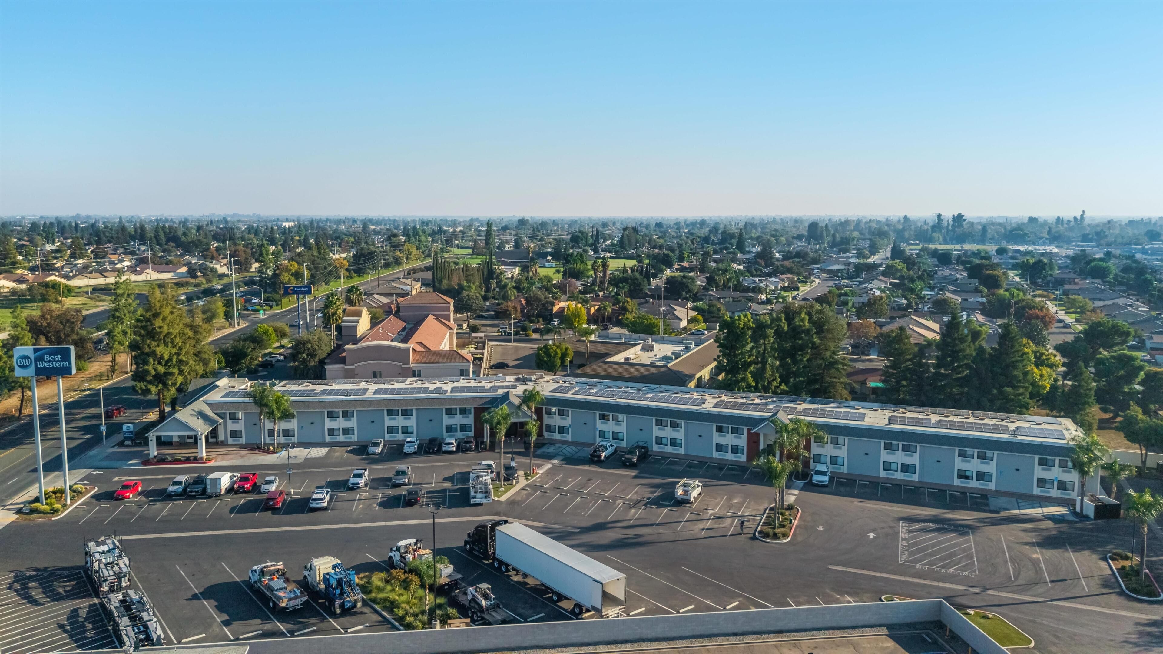 A hotel with a parking lot, a Best Western sign, and a large building with solar panels.
