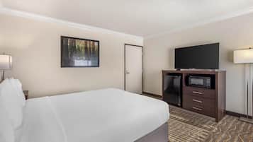 A hotel room with a large bed, a flat-screen TV, a microwave, and a door.