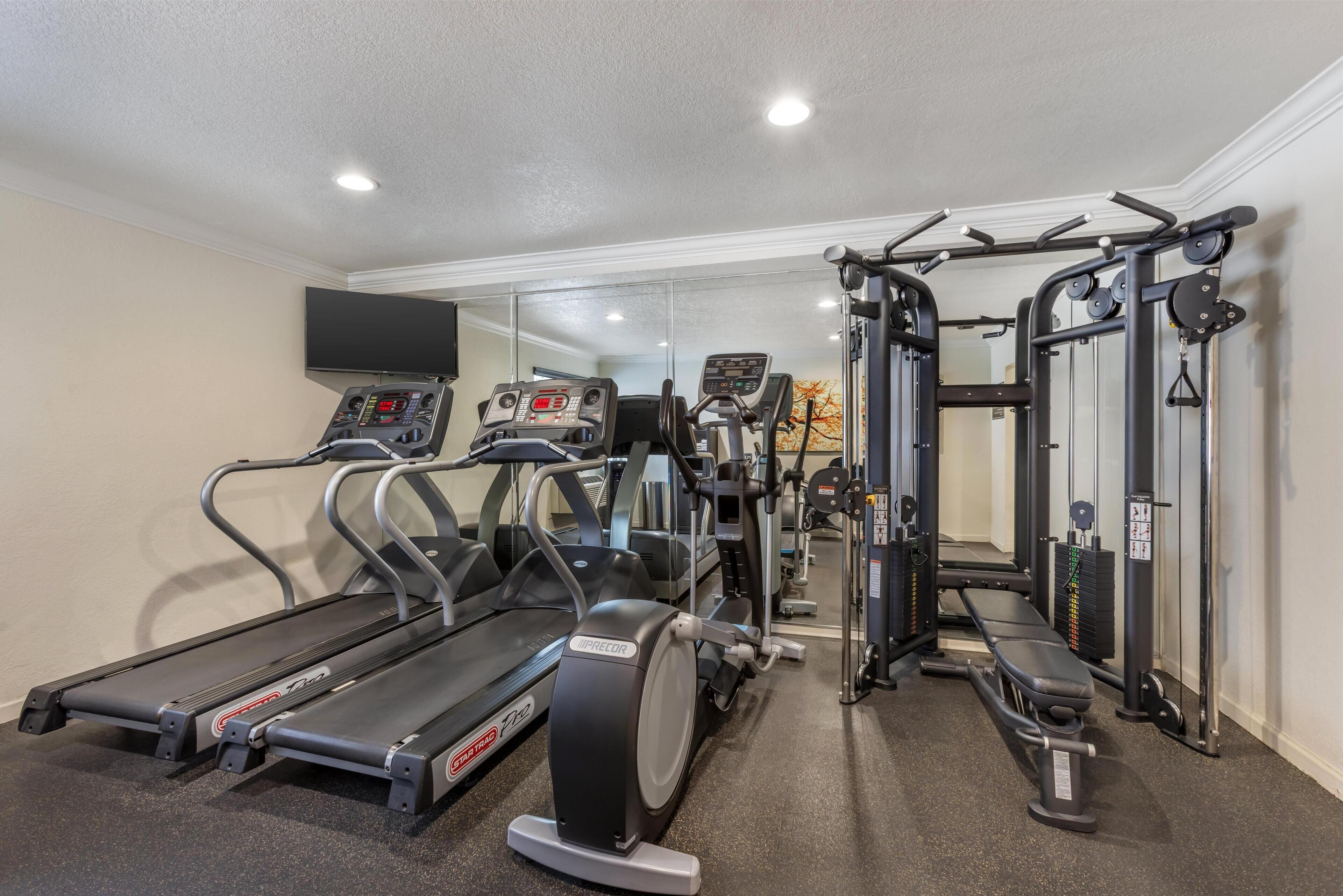 A home gym with treadmills, an elliptical, and a weight machine.