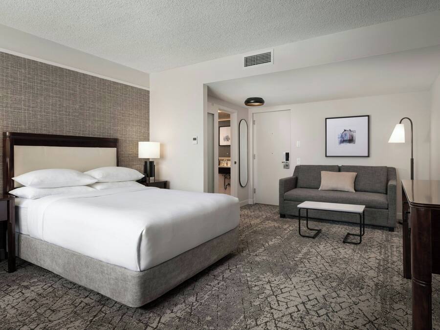 Una habitación de hotel con una cama grande, un sofá, un escritorio y una televisión.