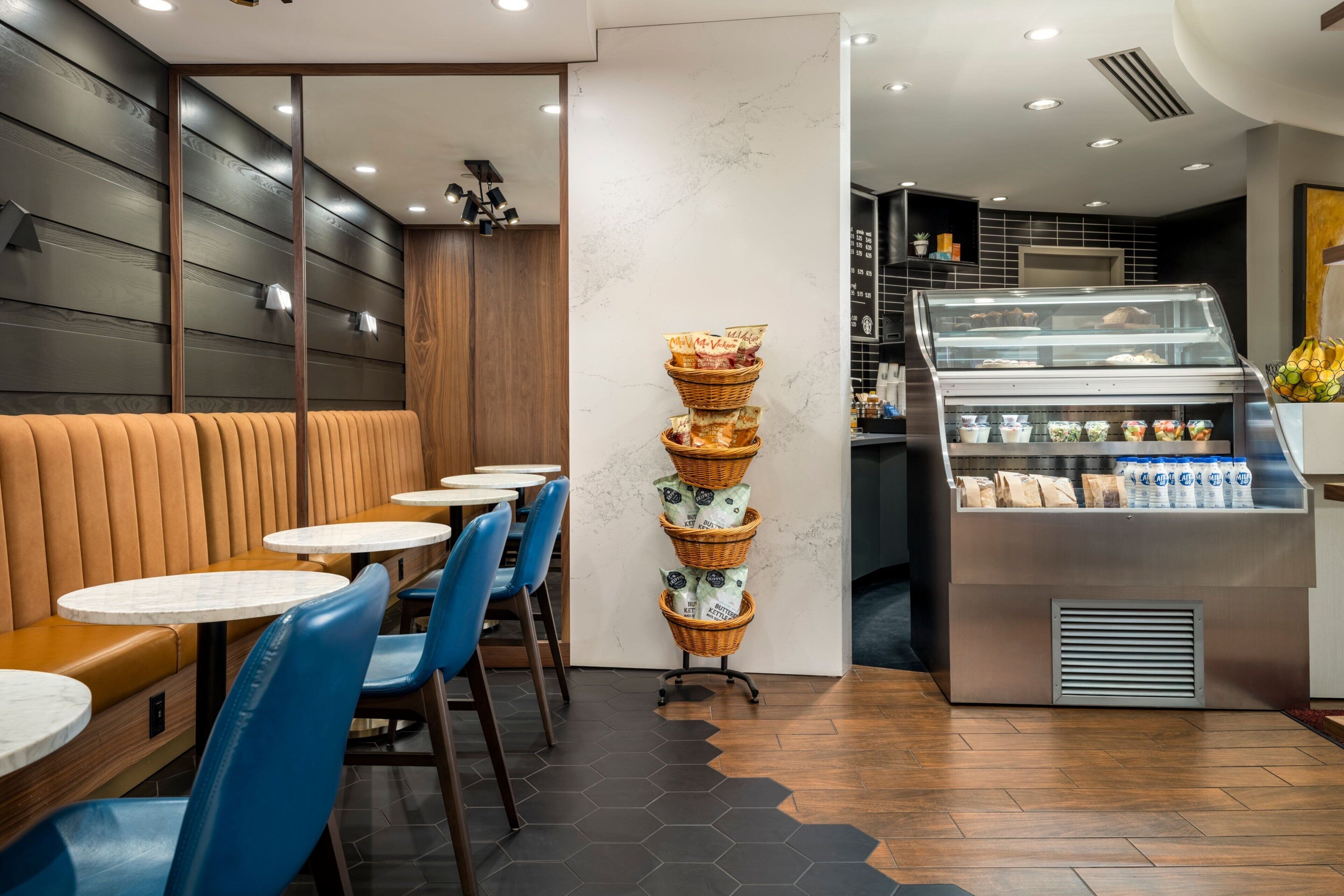 A modern cafe interior with wooden booths, blue chairs, and a display case with baked goods.