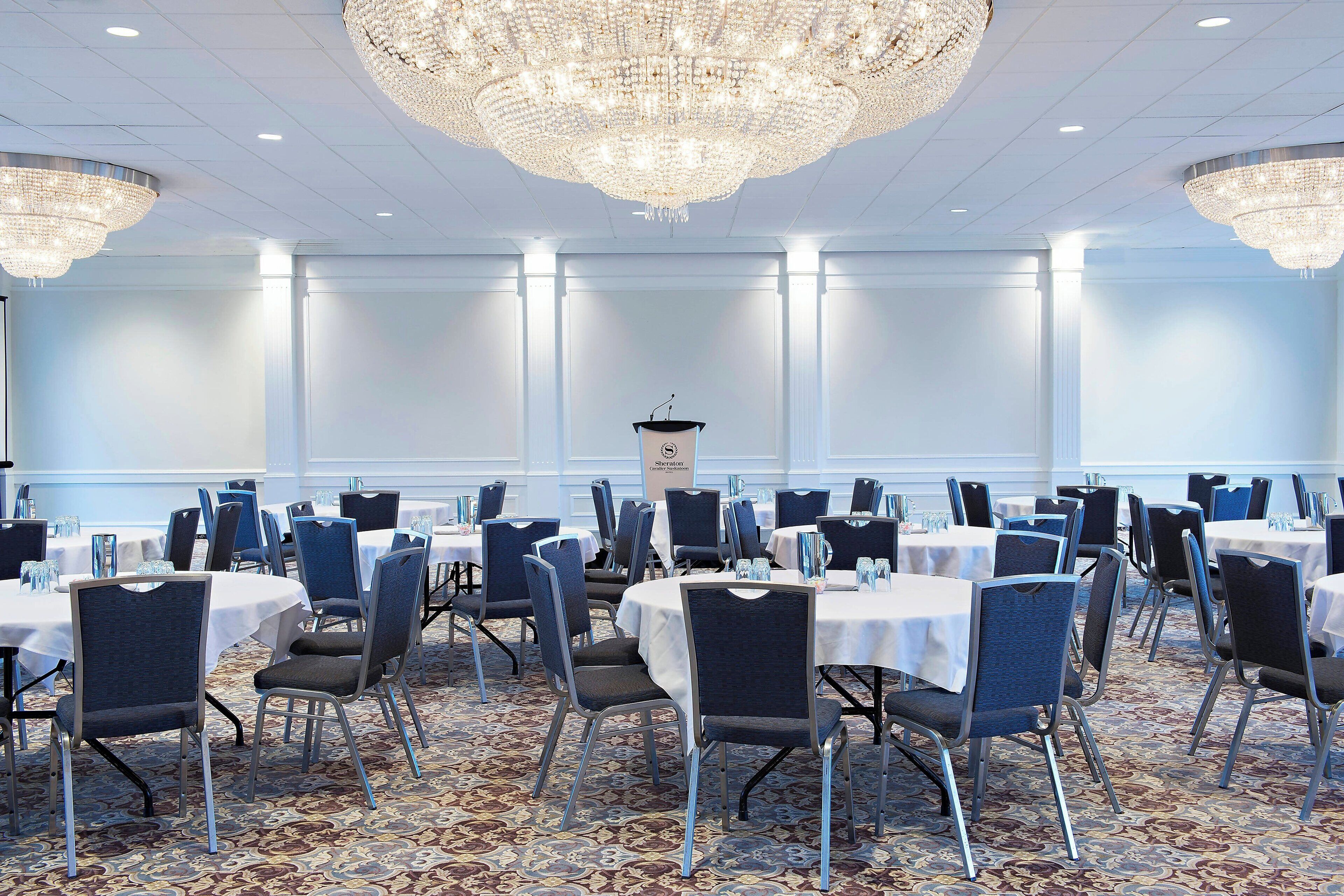 A conference room with round tables, chairs, and a large chandelier.