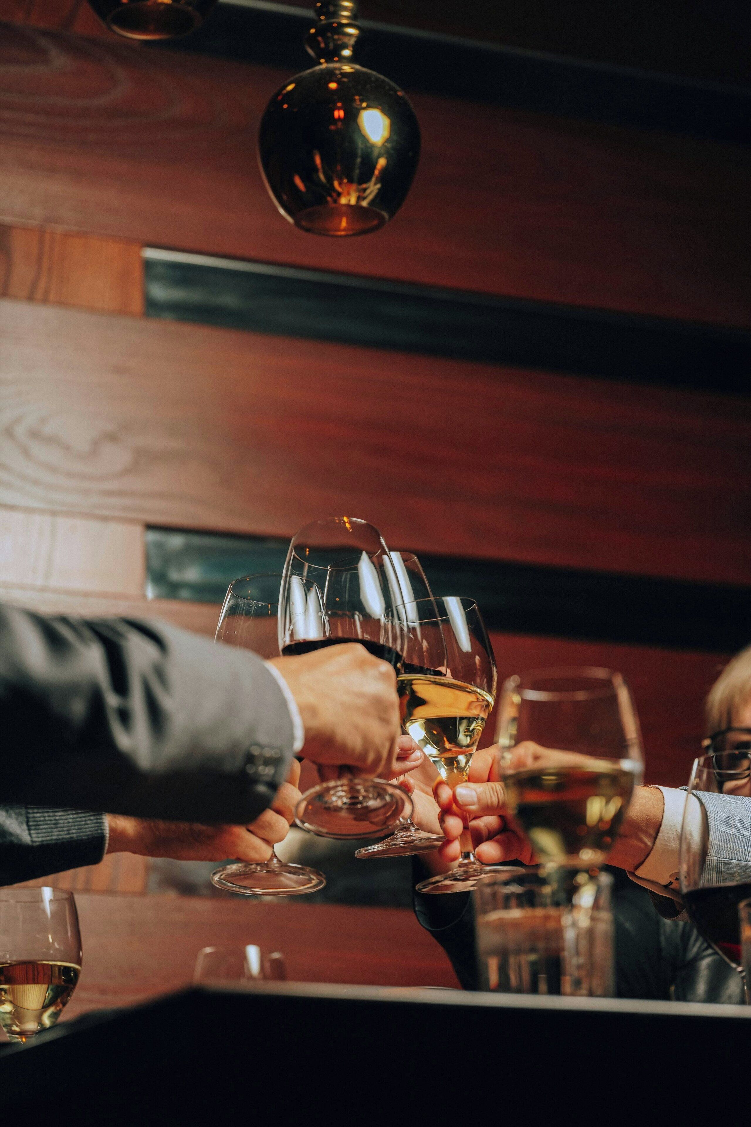A group of people toasting with wine glasses at a bar.
