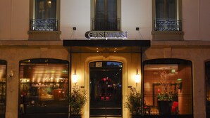 Exterior de un hotel llamado Gastwest, con una entrada destacada, amplias ventanas y plantas en macetas a la entrada.