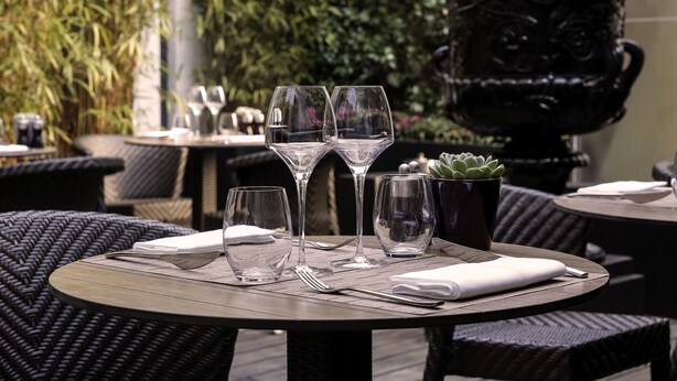 Una mesa dispuesta con copas de vino, una pequeña planta en maceta y una servilleta.