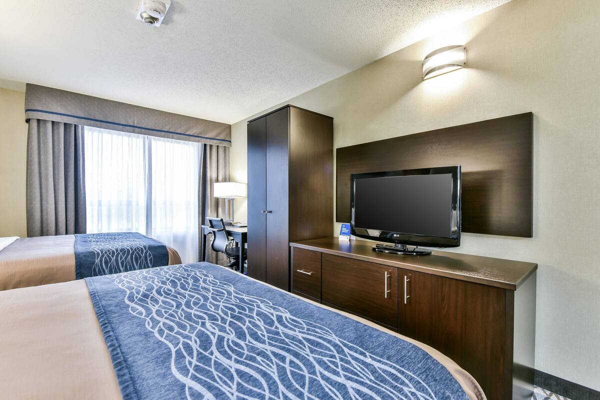 A hotel room with two beds, a desk, a television, and a wardrobe.