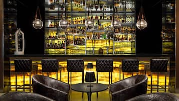 Un espace bar doté de plusieurs étagères remplies de bouteilles, de luminaires suspendus et de fauteuils en cuir.