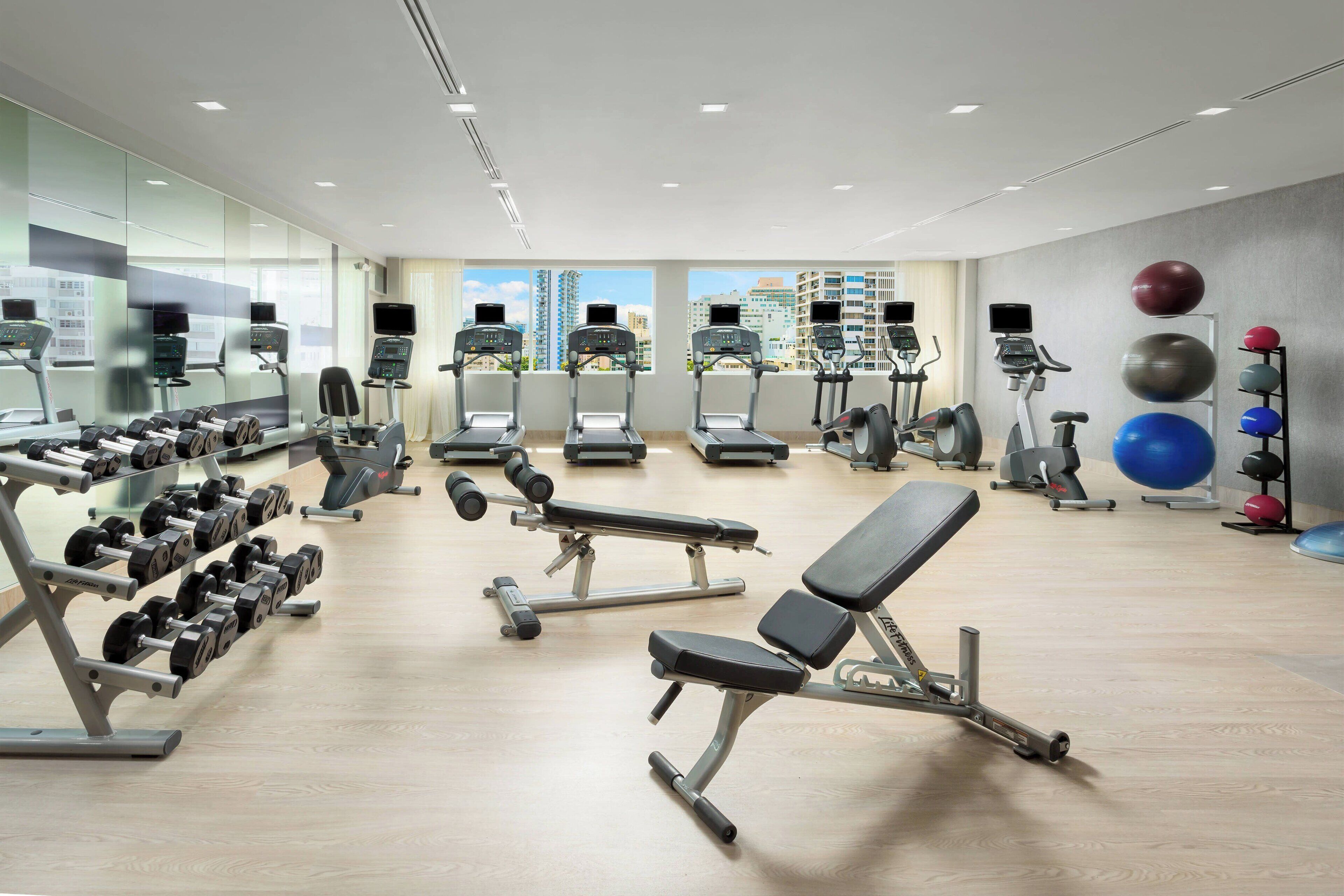 Une salle de sport moderne équipée de tapis de course, d’haltères et de ballons d’exercice.