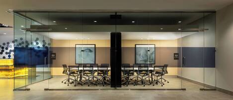 A modern conference room with glass walls, a central table with chairs, and artwork on the walls.