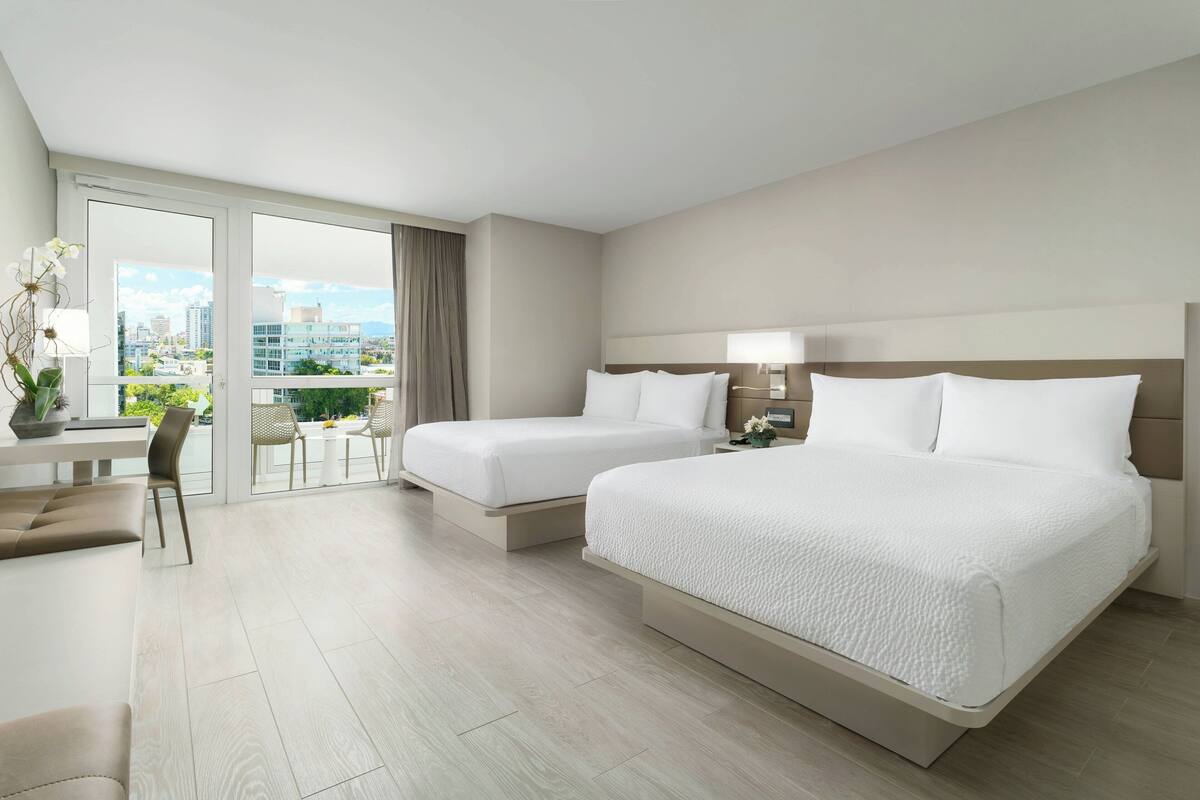 Ein Hotelzimmer mit zwei Betten, einem Schreibtisch und einem Sessel.