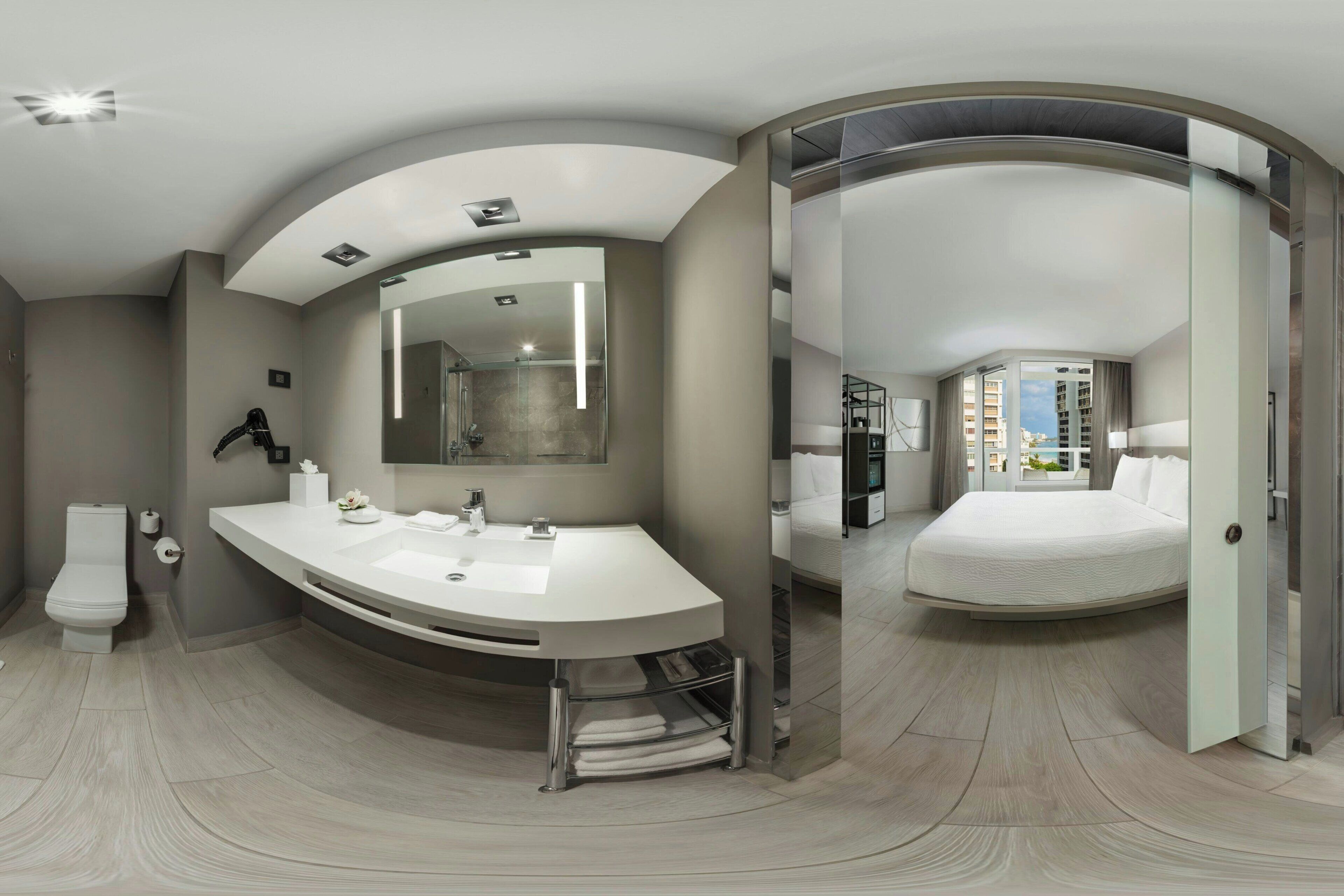 A modern bathroom with a curved sink, a large mirror, and a toilet.