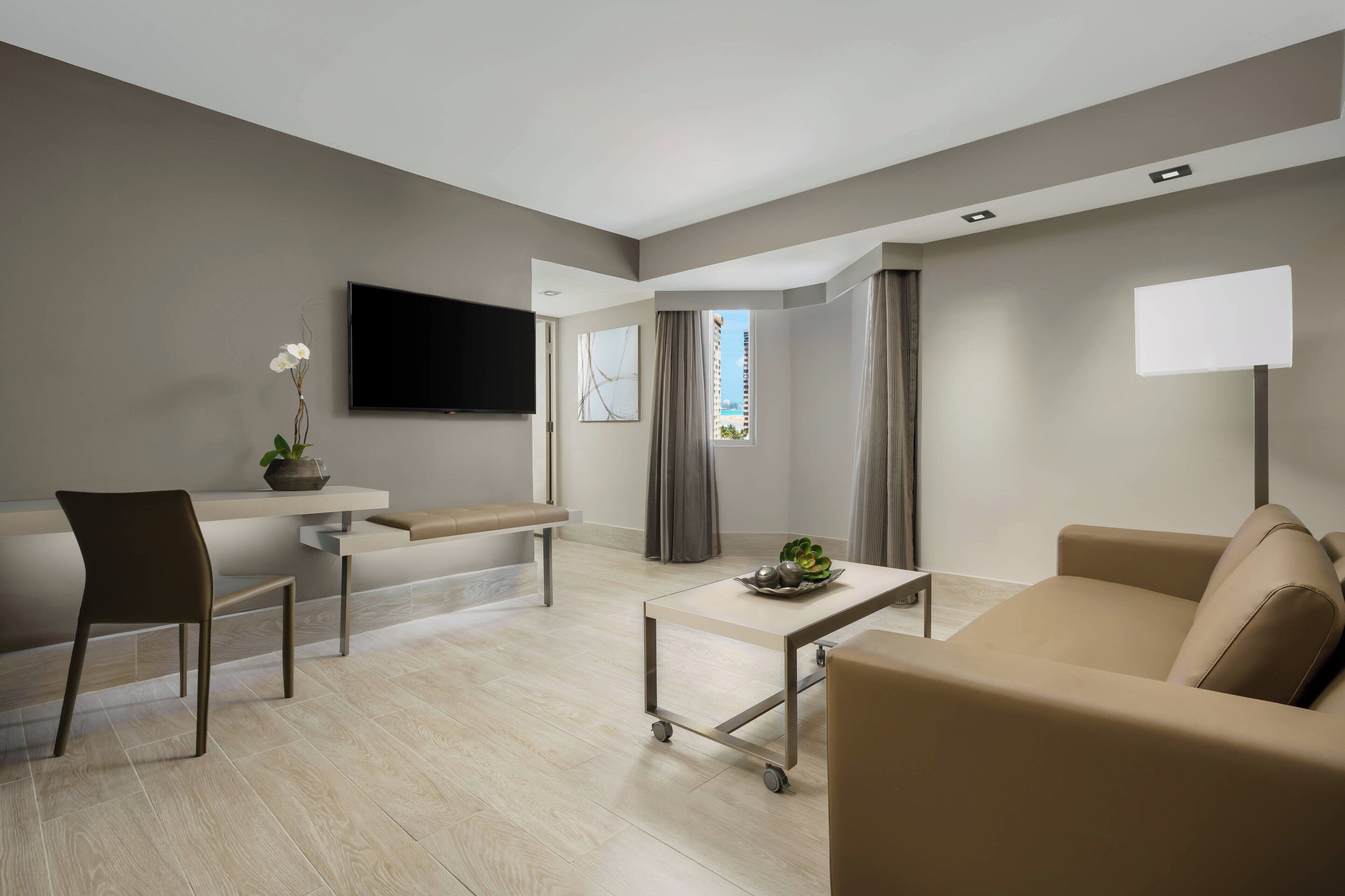 A modern living room with a sofa, a chair, a small table, a TV, and a window with curtains.