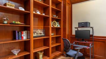 A wooden bookshelf with decorative items, a desk with a computer, and a chair.