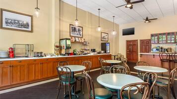 A restaurant with a bar area, wooden cabinets, and multiple tables and chairs.