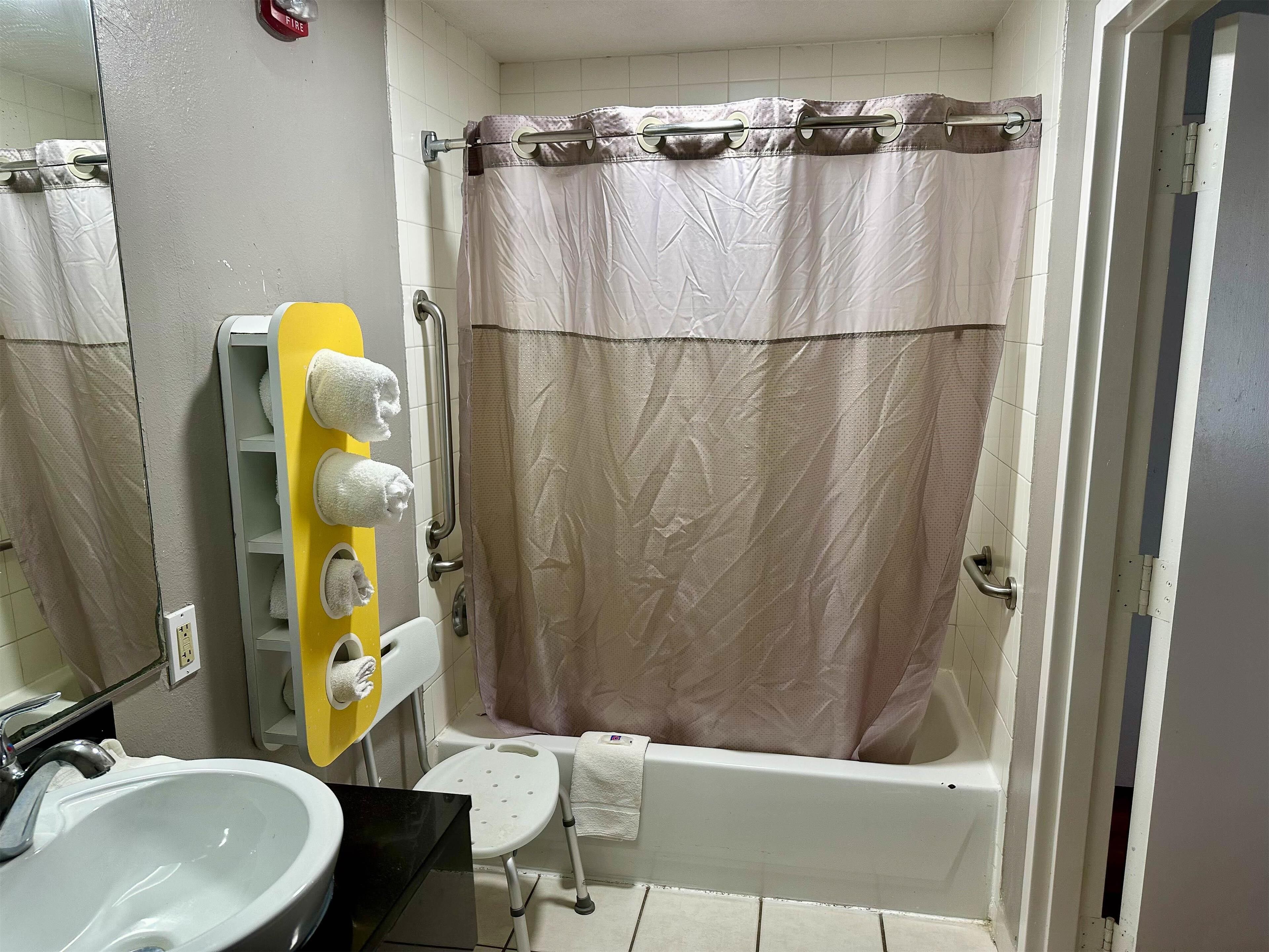 Un baño con bañera, lavabo y toallero con varias toallas.