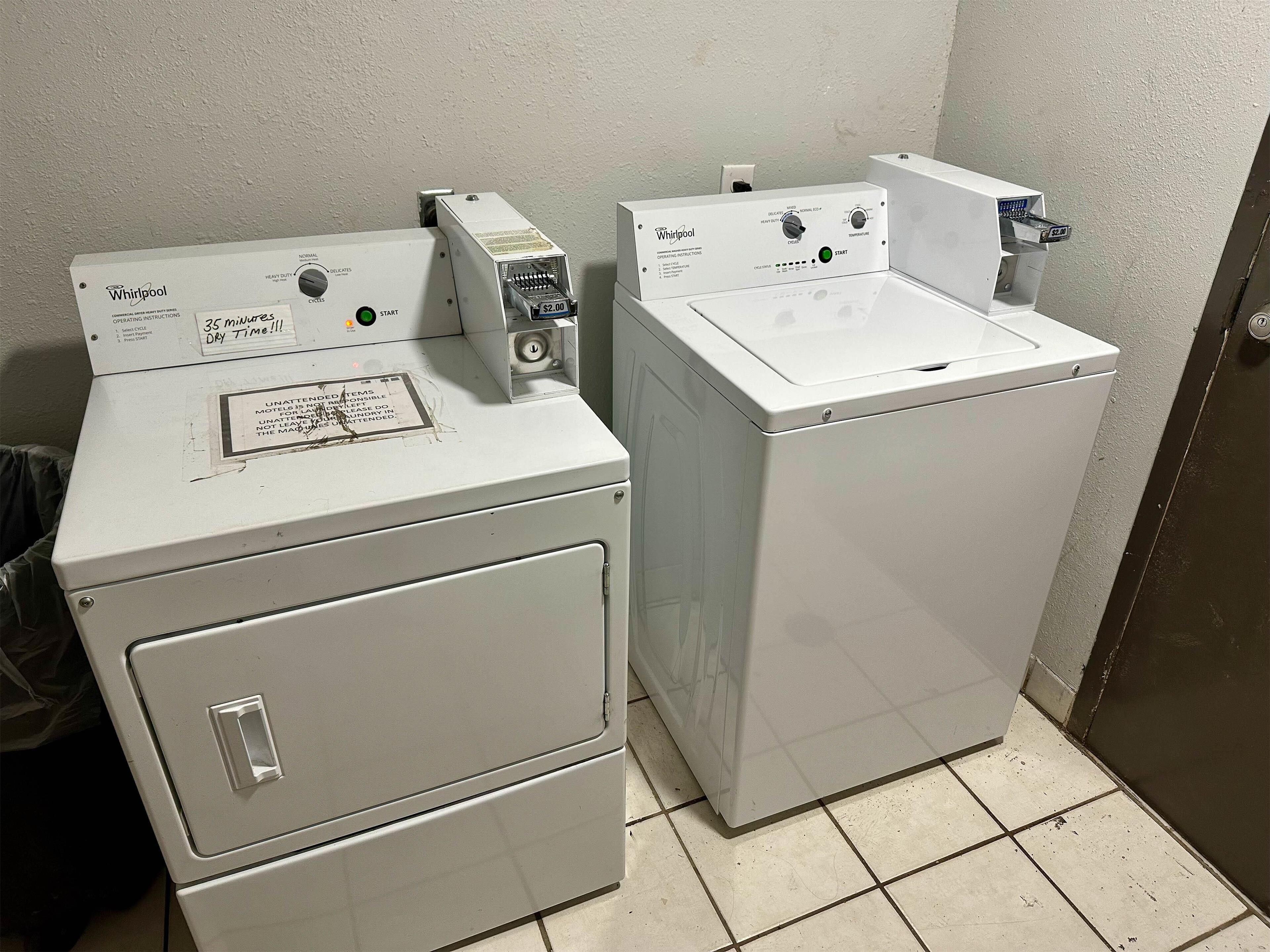 Two stacked Whirlpool front-loading washers in a laundry room with tiled flooring.