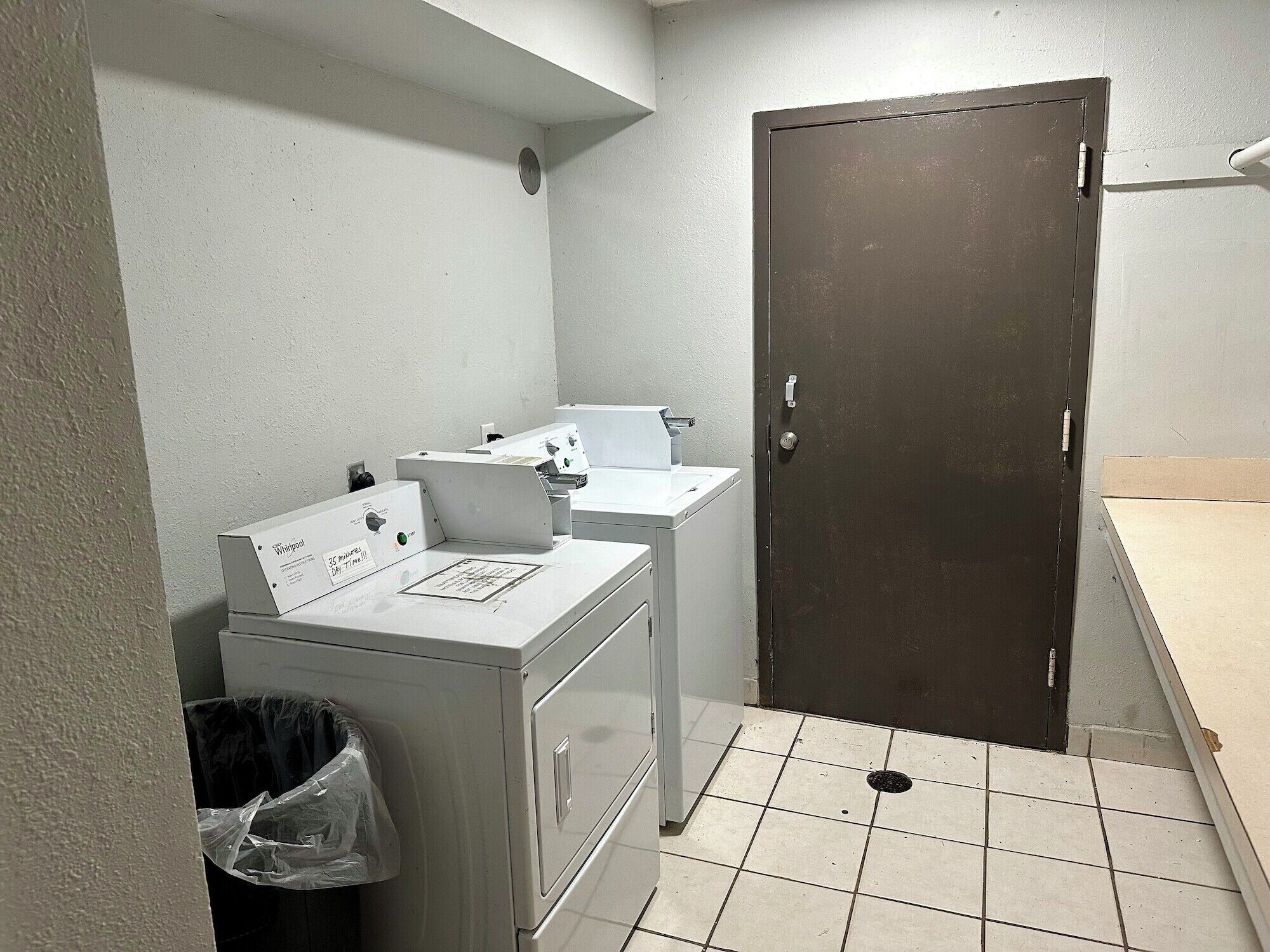 Un cuarto de lavandería con lavadora, secadora y una puerta.
