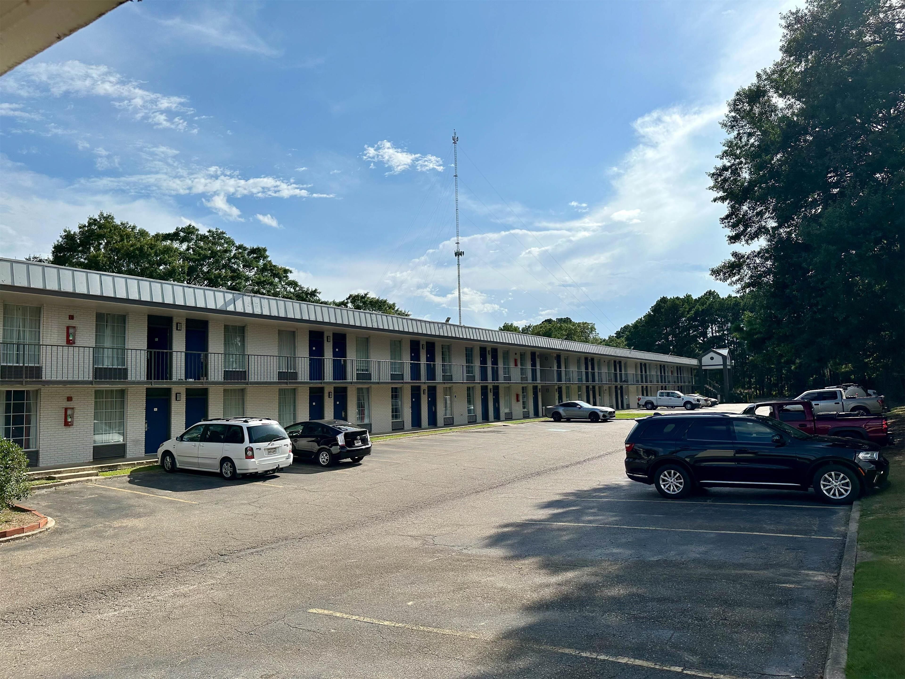 A motel with multiple rooms, a parking lot, and a few cars parked.