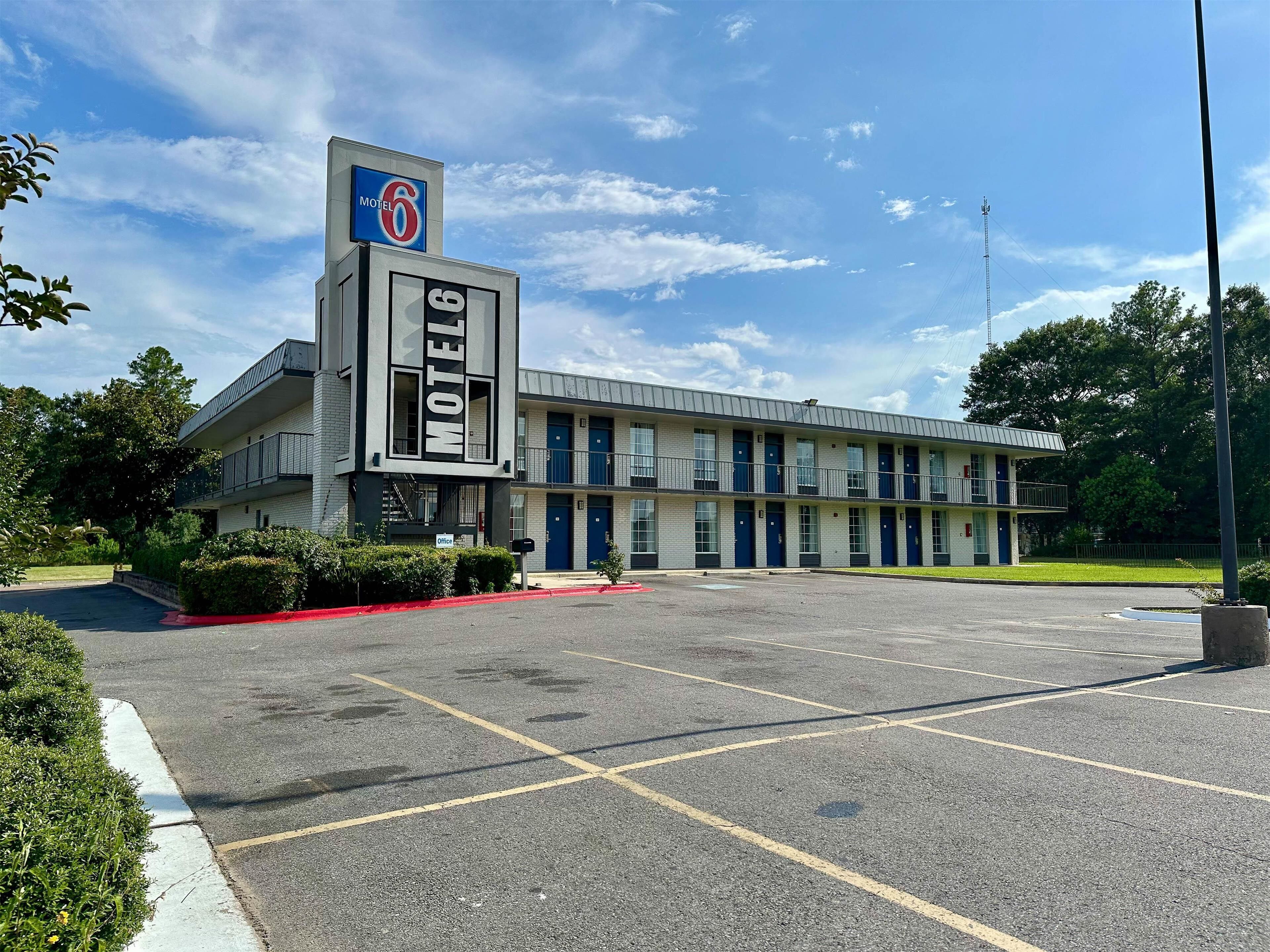 A motel with a prominent 'Motel 6' sign, multiple balconies, and a parking lot.