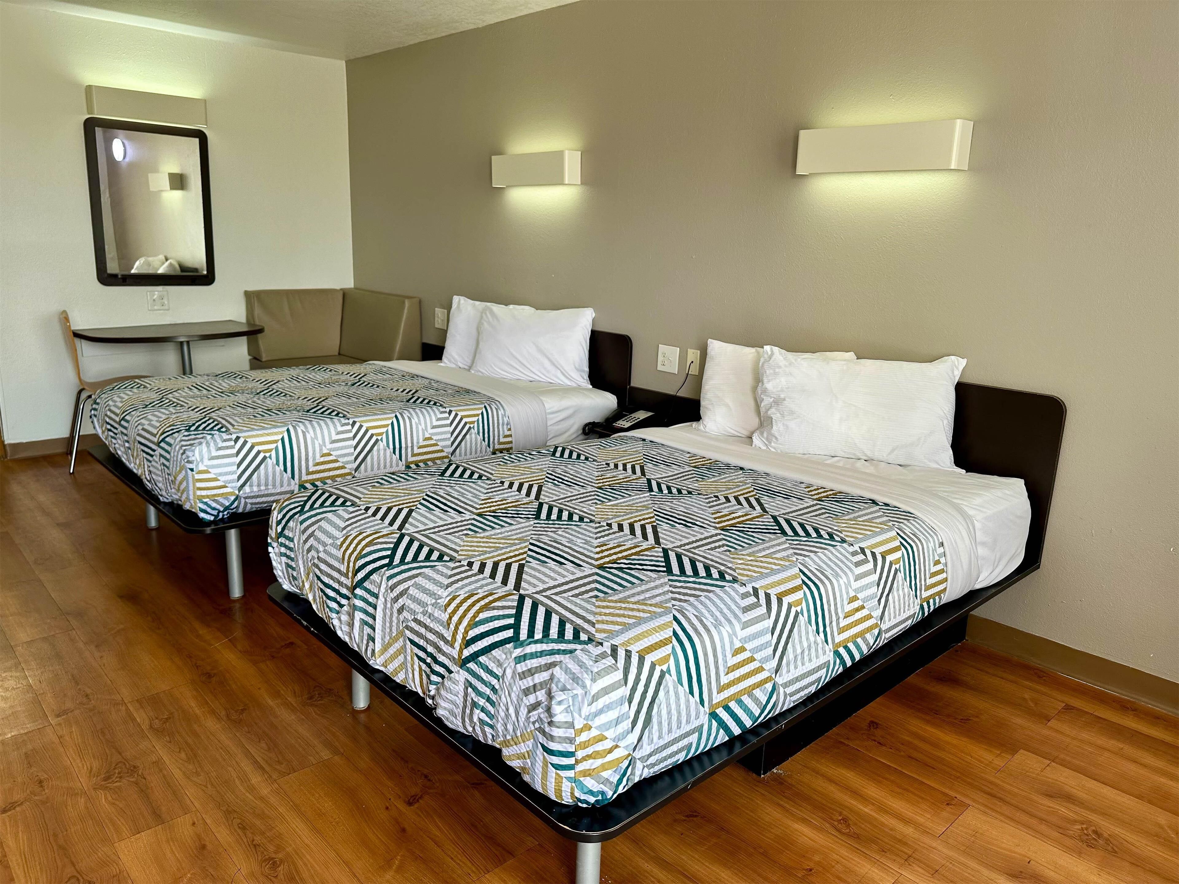 Ein Hotelzimmer mit zwei Betten, einem Schreibtisch und einem Stuhl.
