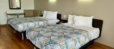 Une chambre d’hôtel avec deux lits, un bureau et une chaise.