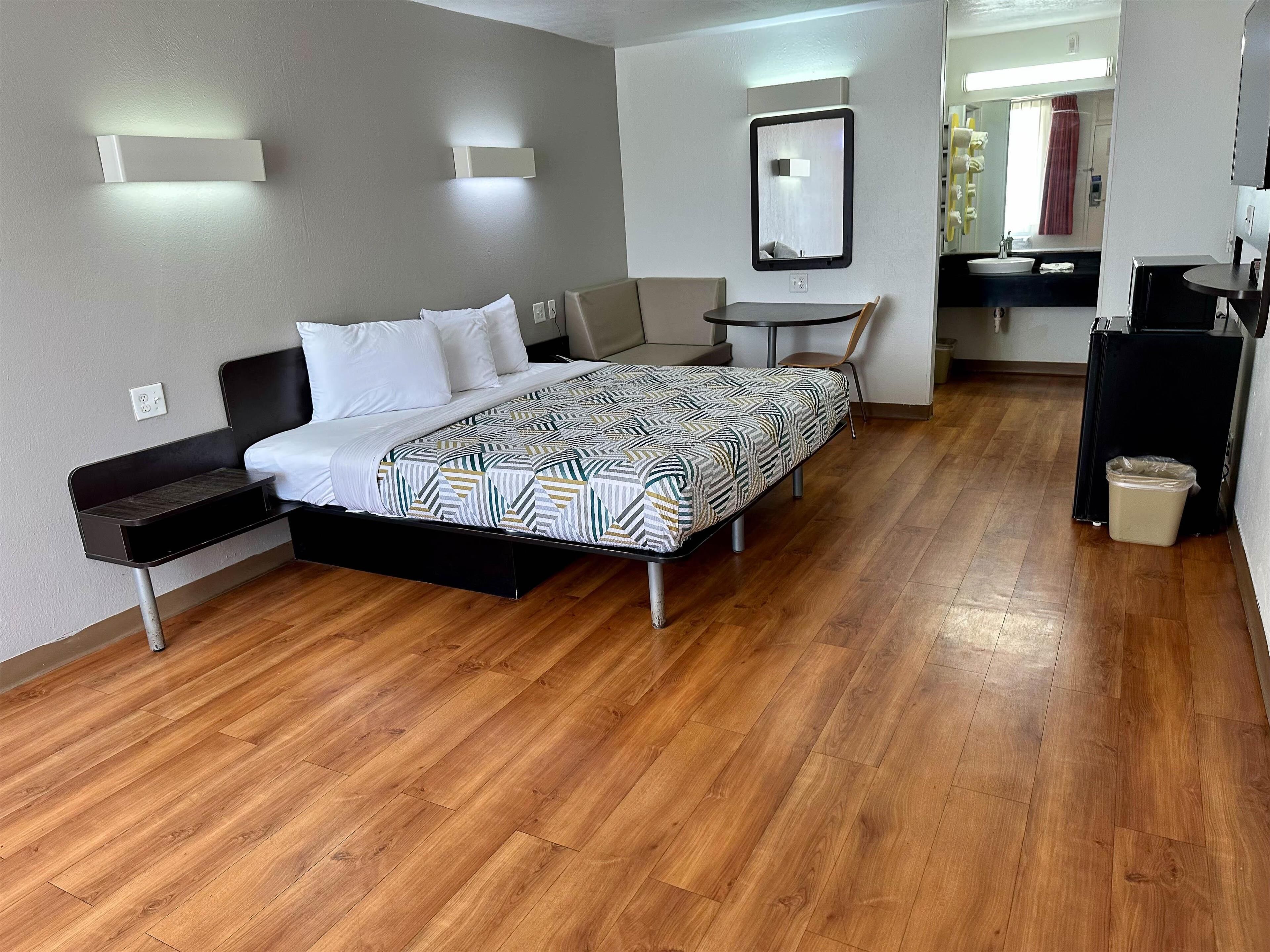 Une chambre d’hôtel comprenant un lit, une table de chevet, une chaise et une petite table avec un miroir.