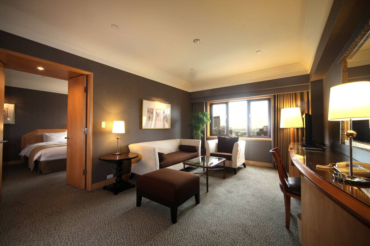 A hotel room with a bed, a sofa, a coffee table, a desk, and a chair.