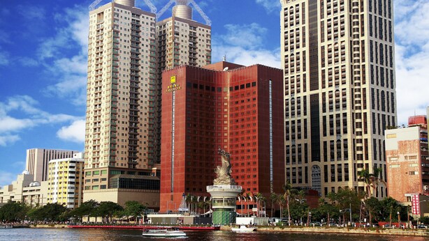 Un hôtel de grande hauteur, avec de nombreux étages, une tour centrale imposante et une vue sur le front de mer.