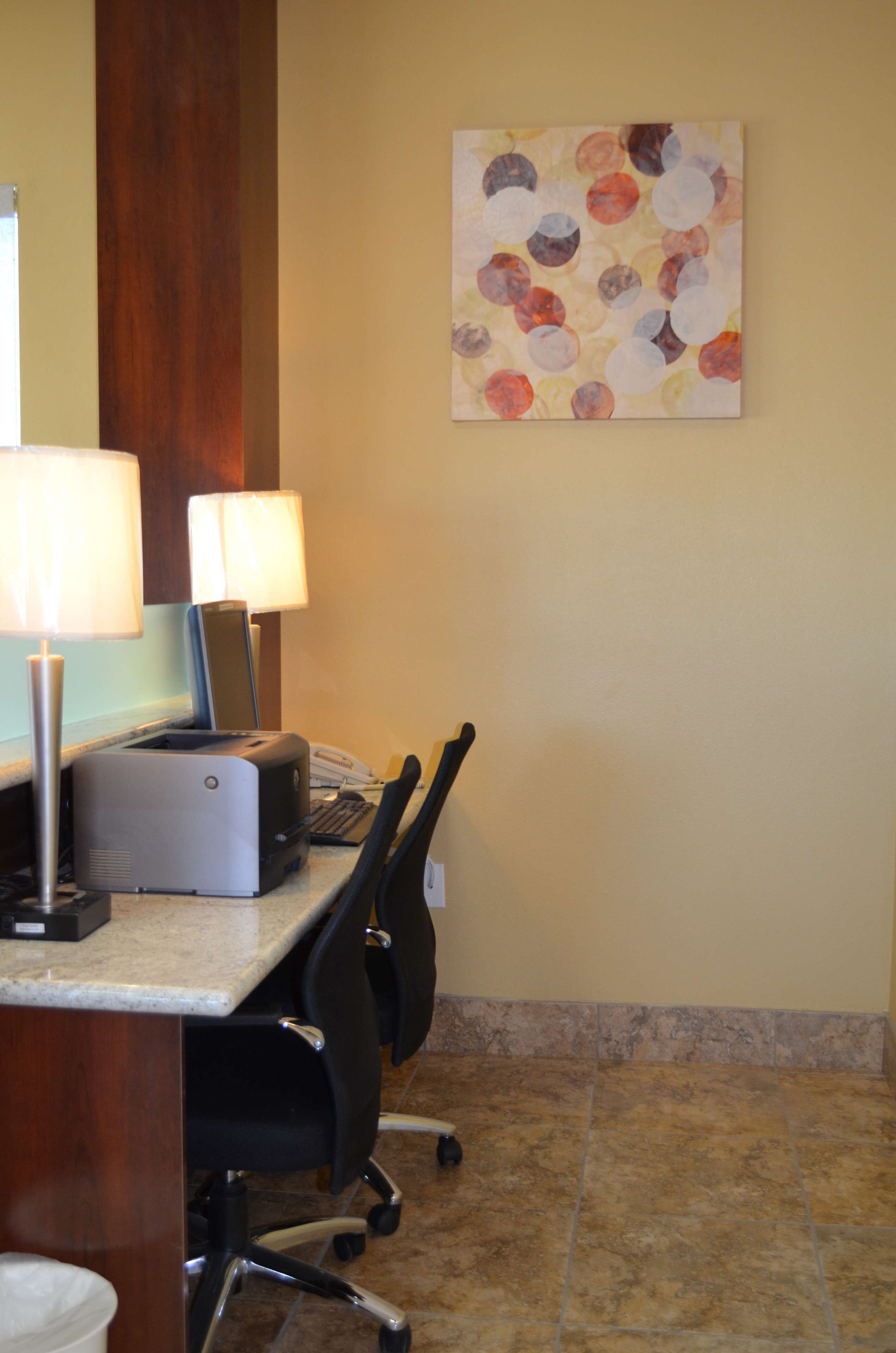 Habitación de hotel con escritorio, dos lámparas, una impresora, teléfono y una silla.