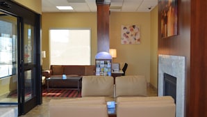 A lobby with a sofa, a coffee table, a fireplace, and a wall-mounted artwork.