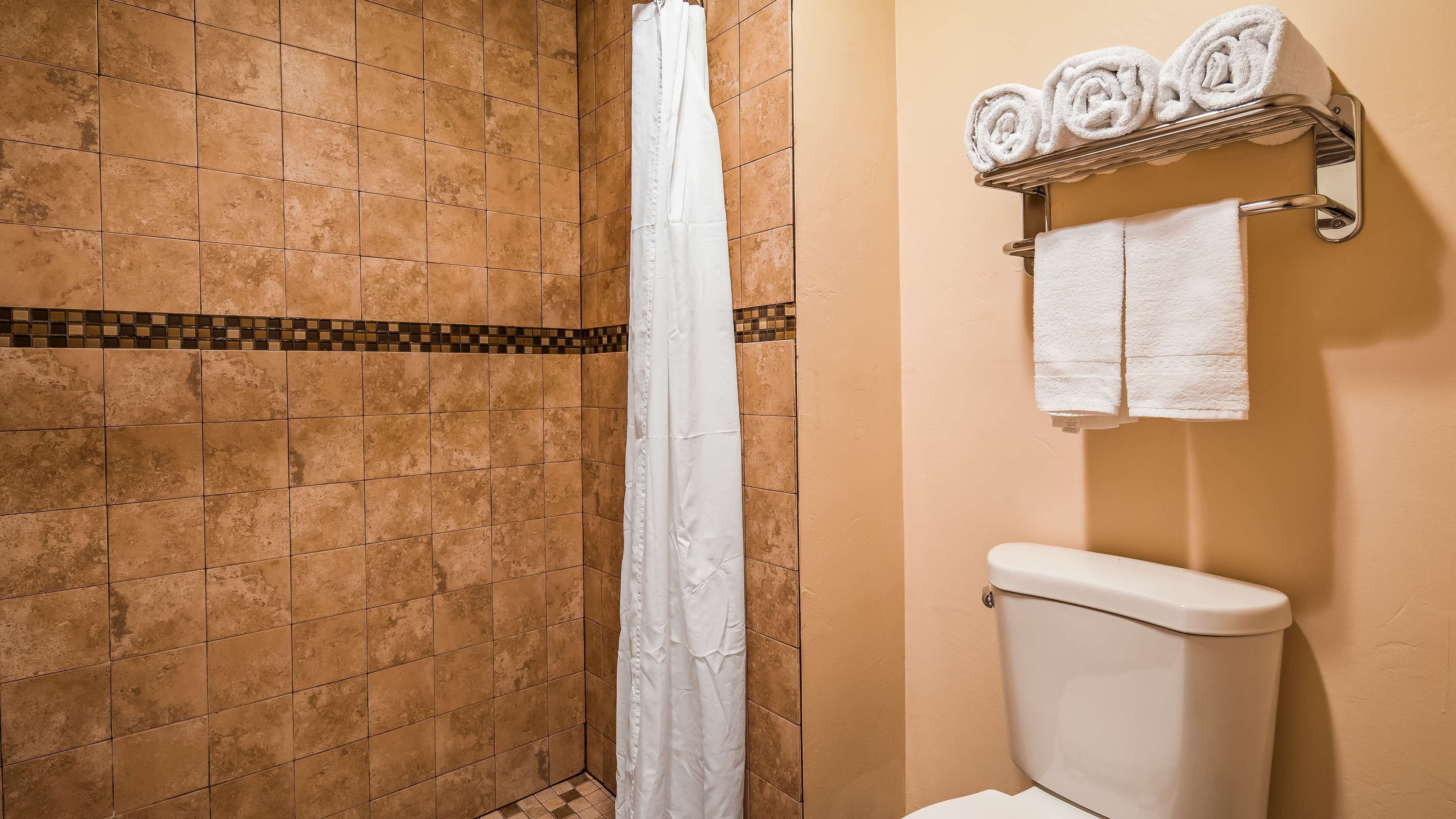Un baño con ducha, inodoro y toallero con toallas.