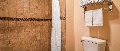 Un baño con ducha, inodoro y toallero con toallas.