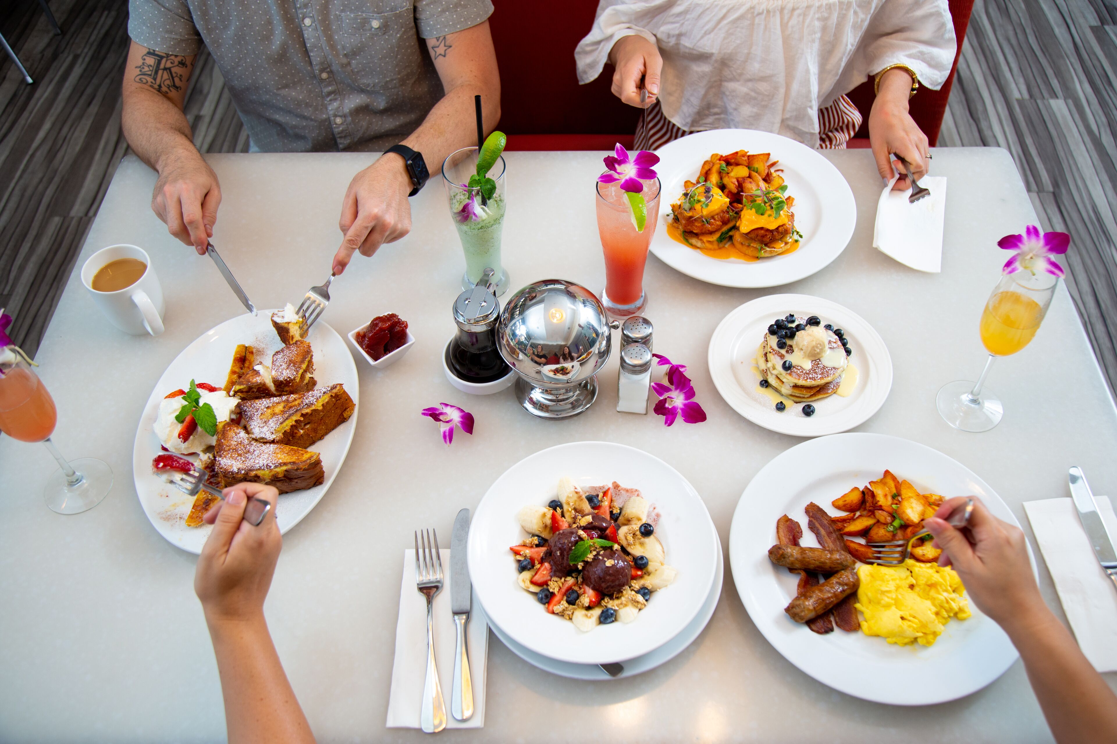 A dining table with various breakfast dishes, drinks, and utensils.