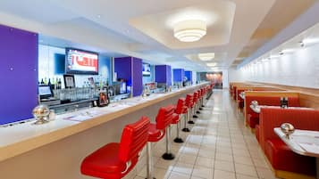 A restaurant with a long counter, red bar stools, and a modern interior design.