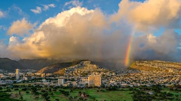 A cityscape with a prominent mountain, a rainbow, and a dense residential area.