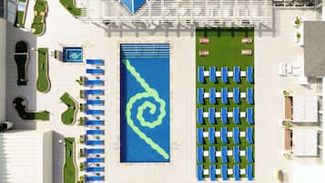 An aerial view of a hotel with a large swimming pool, multiple lounge areas, and a golf course.