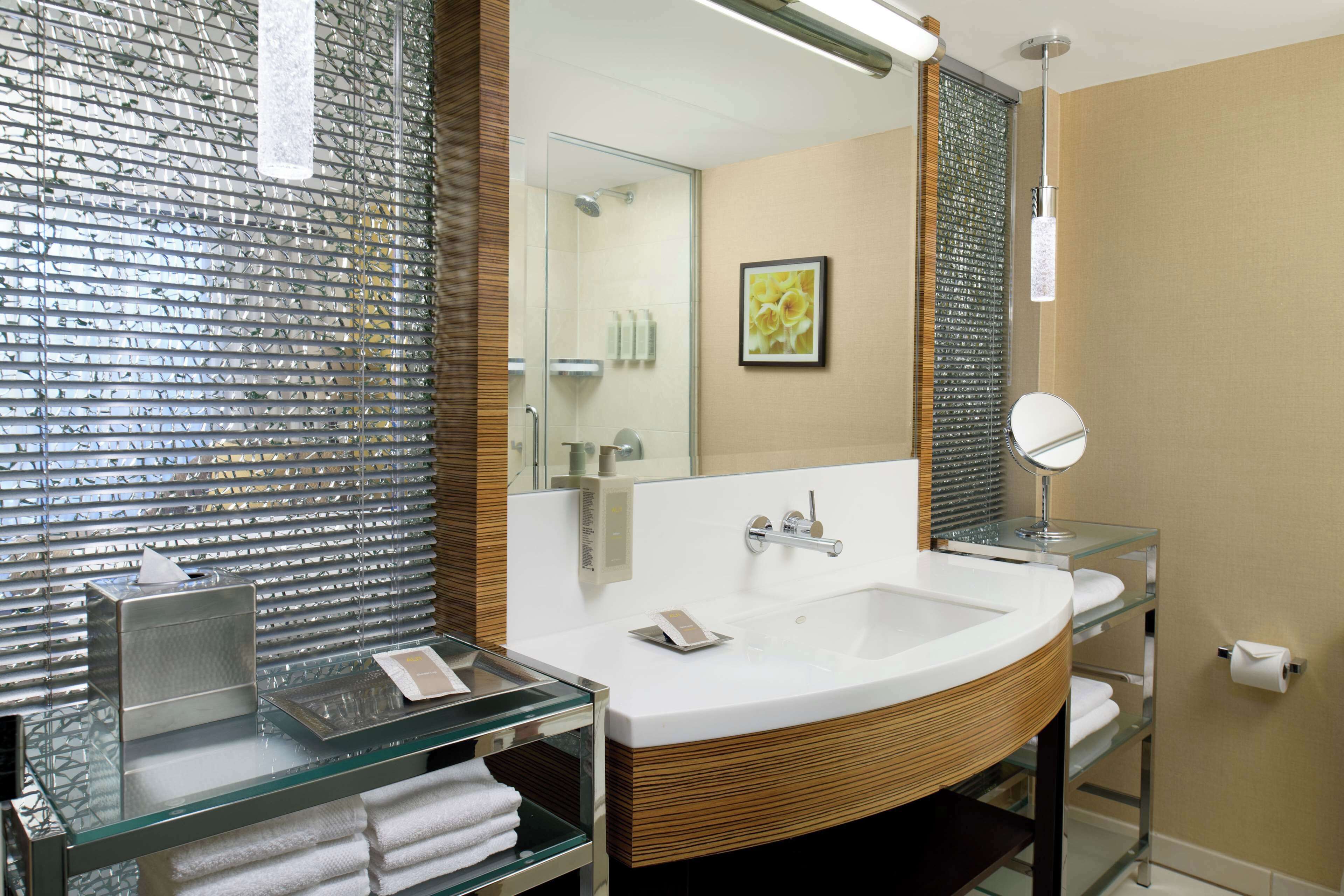 A modern bathroom with a glass-topped vanity, a large mirror, and a white sink.