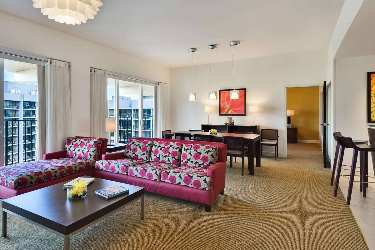 A modern living room with a sectional sofa, a coffee table, and a dining area with a table and chairs.